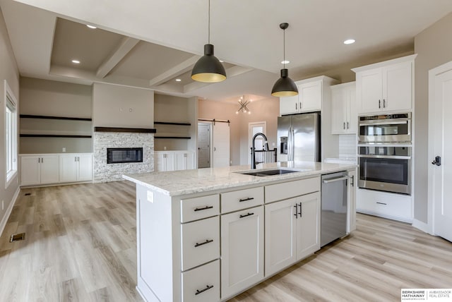 kitchen with light wood finished floors, visible vents, a barn door, stainless steel appliances, and a sink