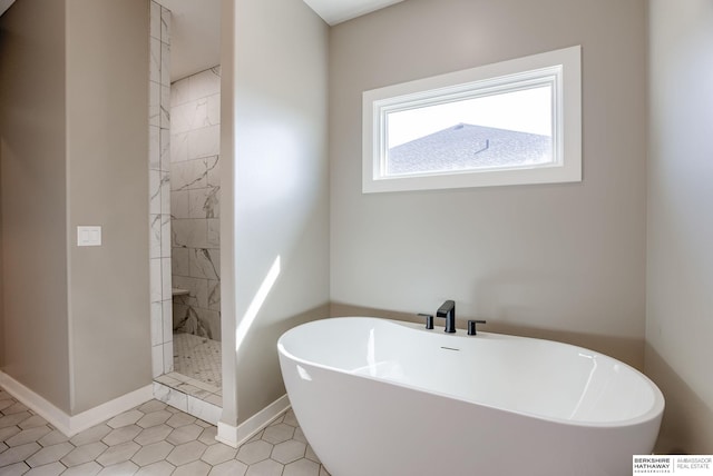 bathroom featuring baseboards, a freestanding bath, and a tile shower