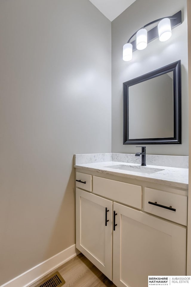 bathroom featuring vanity, visible vents, wood finished floors, and baseboards