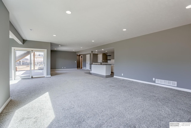 unfurnished living room with recessed lighting, visible vents, light carpet, and baseboards