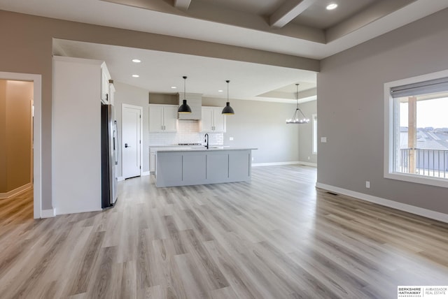 kitchen with light wood-style flooring, baseboards, tasteful backsplash, and freestanding refrigerator