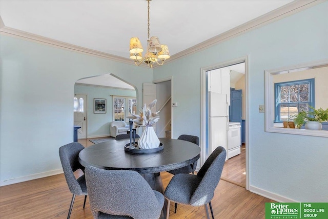 dining space featuring arched walkways, a wealth of natural light, light wood-type flooring, and an inviting chandelier