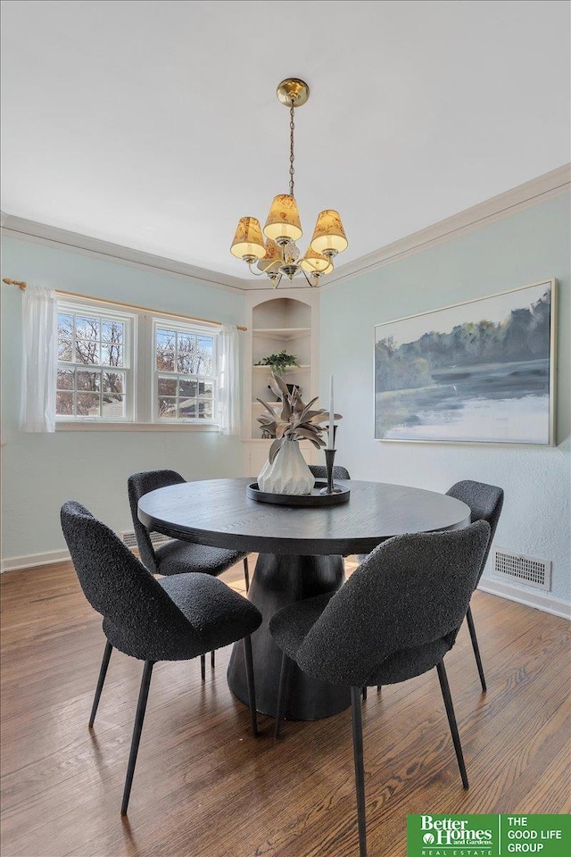 dining space featuring baseboards, wood finished floors, visible vents, and a chandelier