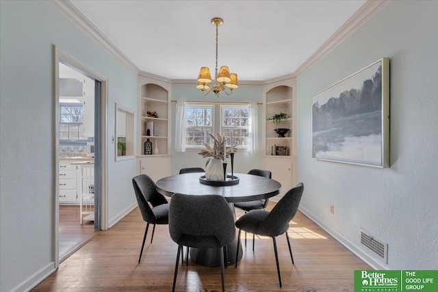 dining room with visible vents, baseboards, ornamental molding, an inviting chandelier, and wood finished floors