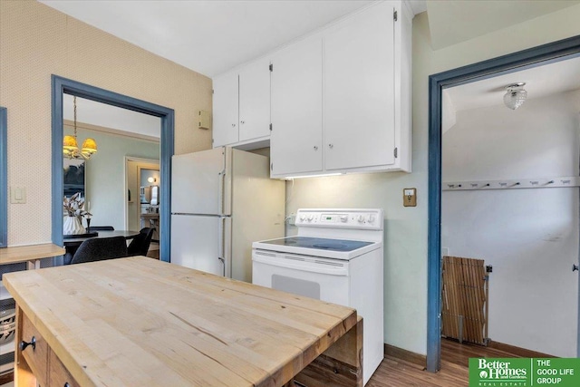 kitchen featuring white appliances, wood finished floors, baseboards, an inviting chandelier, and white cabinets