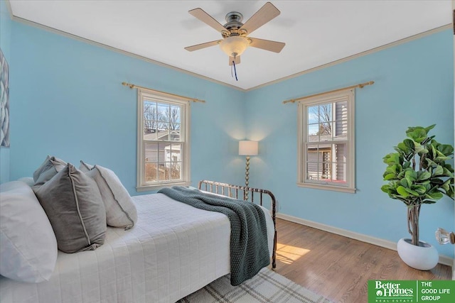 bedroom with multiple windows, crown molding, baseboards, and wood finished floors