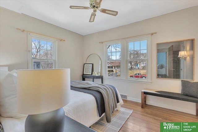 bedroom with visible vents, multiple windows, baseboards, and wood finished floors