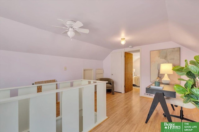 hallway with light wood-style floors and vaulted ceiling