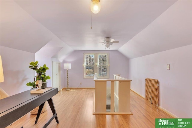 home office with a ceiling fan, lofted ceiling, light wood-style floors, and baseboards