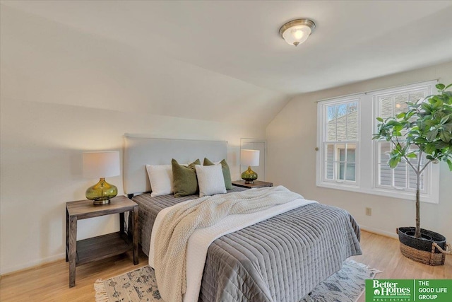 bedroom with lofted ceiling, light wood-style flooring, and baseboards