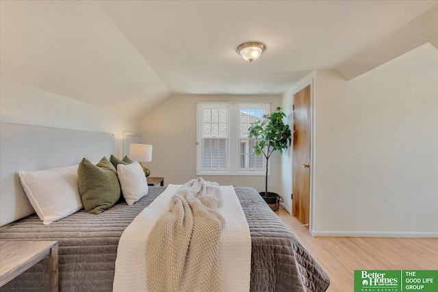 bedroom with lofted ceiling, light wood-style flooring, and baseboards