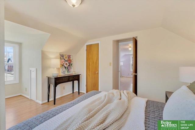 bedroom featuring baseboards, lofted ceiling, and wood finished floors