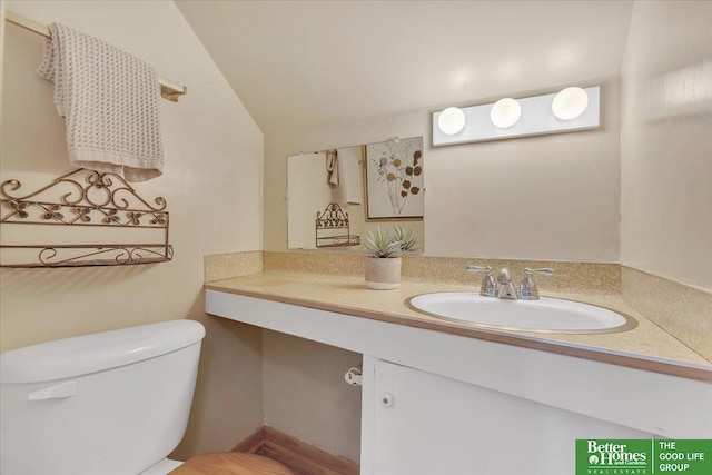 bathroom with toilet, vanity, and lofted ceiling