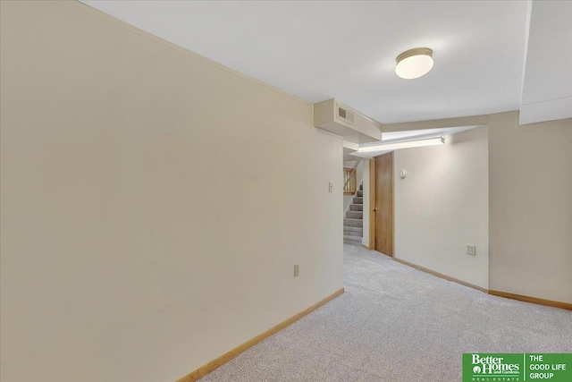 carpeted spare room featuring visible vents, baseboards, and stairs