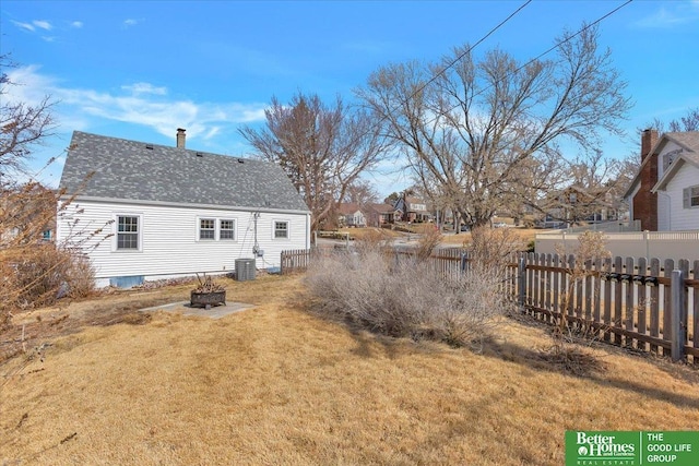 back of property featuring a fire pit, fence, central air condition unit, a lawn, and a chimney