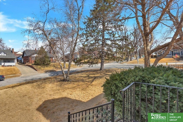 view of yard featuring a residential view and concrete driveway