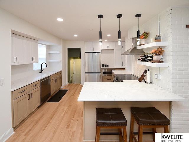 kitchen featuring dishwashing machine, open shelves, a peninsula, a sink, and stainless steel refrigerator