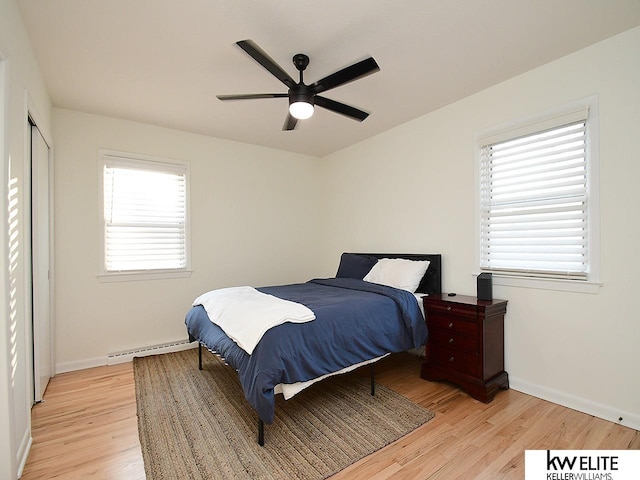 bedroom featuring a ceiling fan, light wood-style floors, baseboards, and a baseboard radiator