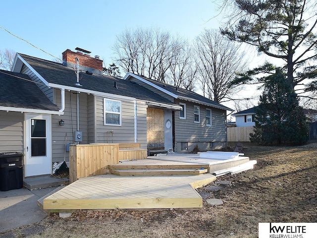 back of property featuring a chimney, a deck, and fence