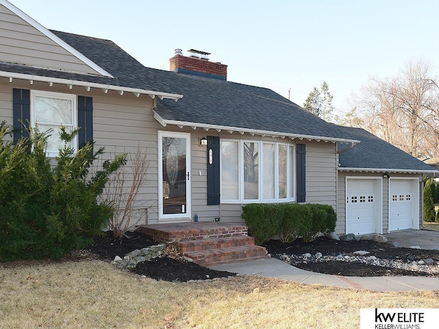 view of front of house featuring an attached garage, roof with shingles, and a chimney