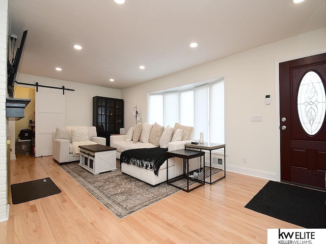 living room with recessed lighting, baseboards, light wood-style floors, and a barn door