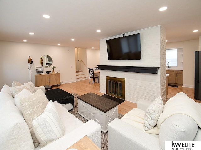 living area with recessed lighting, stairway, a fireplace, light wood finished floors, and baseboards