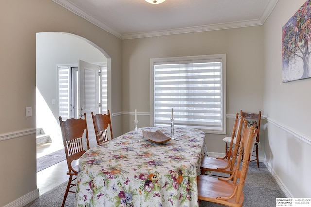 dining room with arched walkways, crown molding, and baseboards