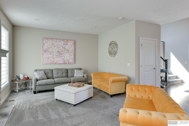 carpeted living area with stairway, baseboards, and visible vents