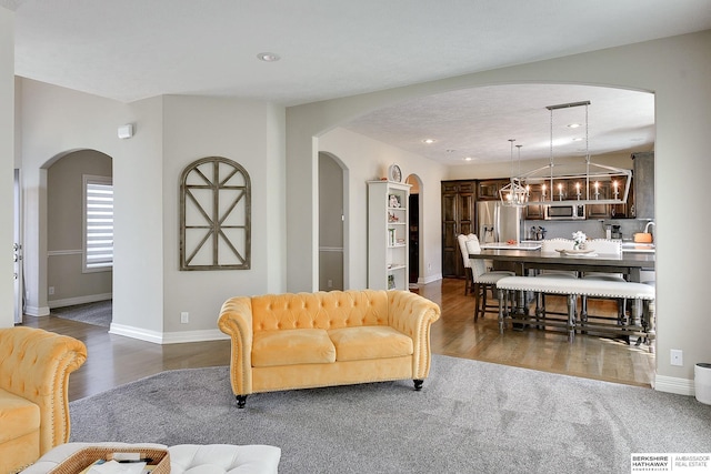 living area featuring dark wood-type flooring, recessed lighting, baseboards, and arched walkways