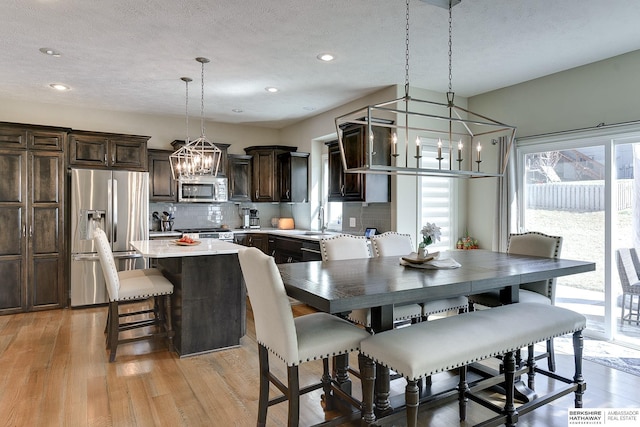 dining area featuring light wood-style flooring, a notable chandelier, recessed lighting, and a textured ceiling