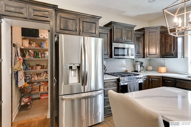 kitchen featuring light wood-type flooring, light stone counters, tasteful backsplash, stainless steel appliances, and dark brown cabinetry