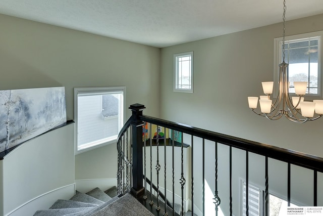 staircase with a notable chandelier