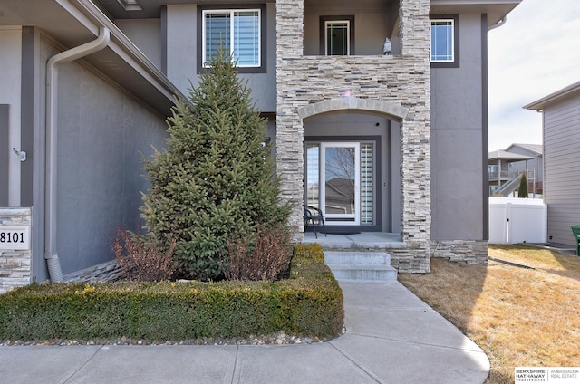 doorway to property featuring stone siding and stucco siding