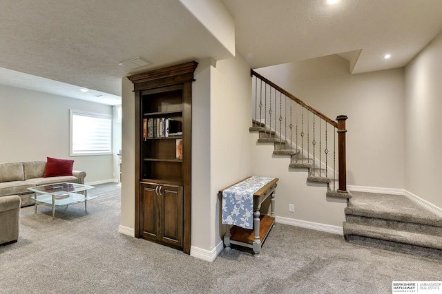 staircase featuring visible vents, carpet, baseboards, and a textured ceiling