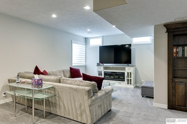 carpeted living area with recessed lighting, baseboards, a textured ceiling, and a glass covered fireplace