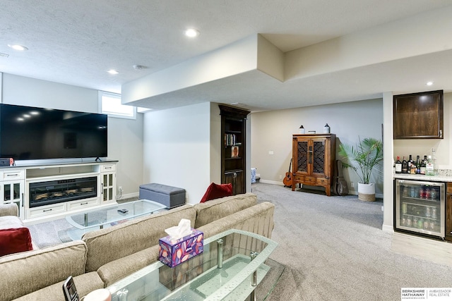 living area with baseboards, wine cooler, light carpet, a textured ceiling, and a bar