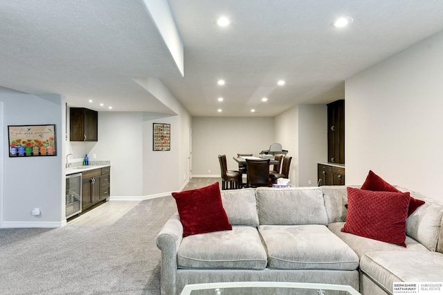 living room featuring beverage cooler, baseboards, recessed lighting, bar area, and light colored carpet