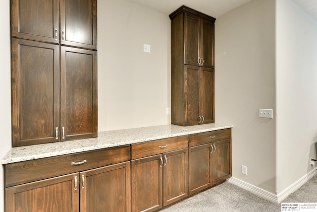 interior space with light stone counters, baseboards, and light carpet