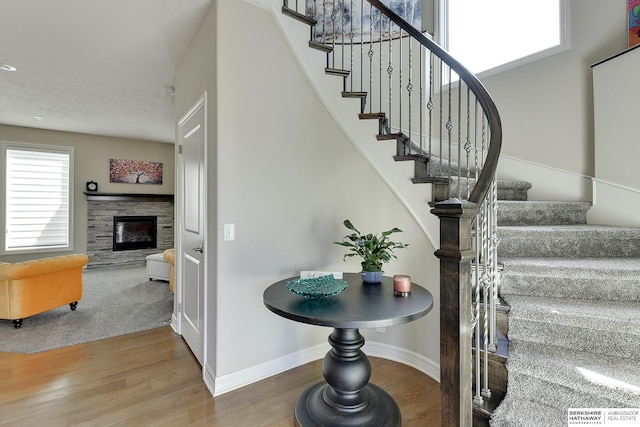 interior space featuring stairway, baseboards, wood finished floors, and a fireplace