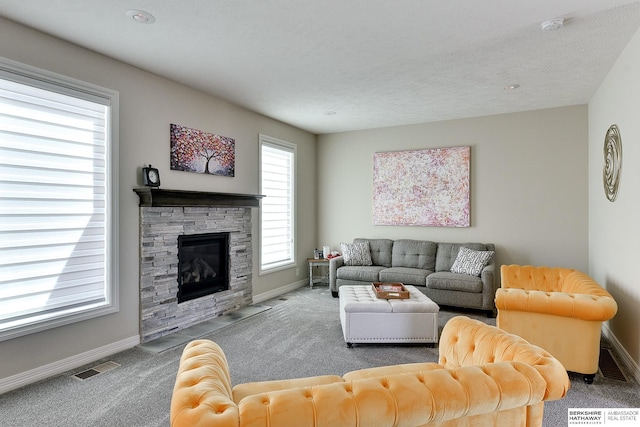 living area with a stone fireplace, visible vents, baseboards, and carpet floors