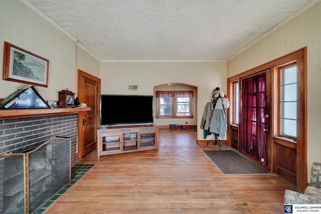 foyer with visible vents, ornamental molding, a fireplace, wood finished floors, and a textured ceiling