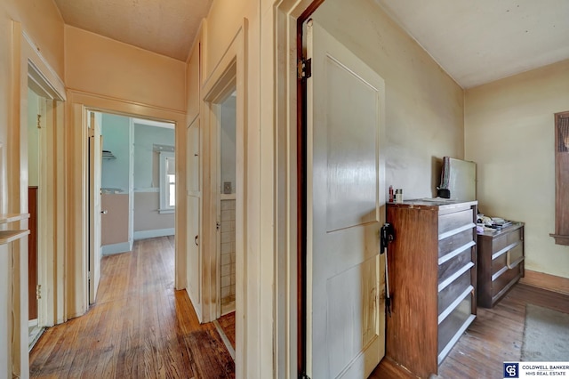 corridor featuring baseboards and hardwood / wood-style flooring