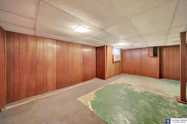 finished below grade area with a paneled ceiling and wood walls