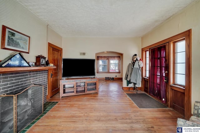 entrance foyer featuring visible vents, a textured ceiling, wood finished floors, and a fireplace