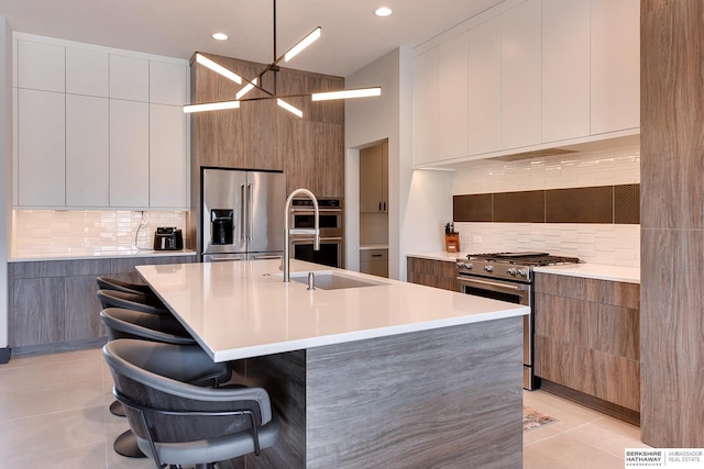 kitchen with light tile patterned floors, a kitchen breakfast bar, modern cabinets, high end appliances, and a sink