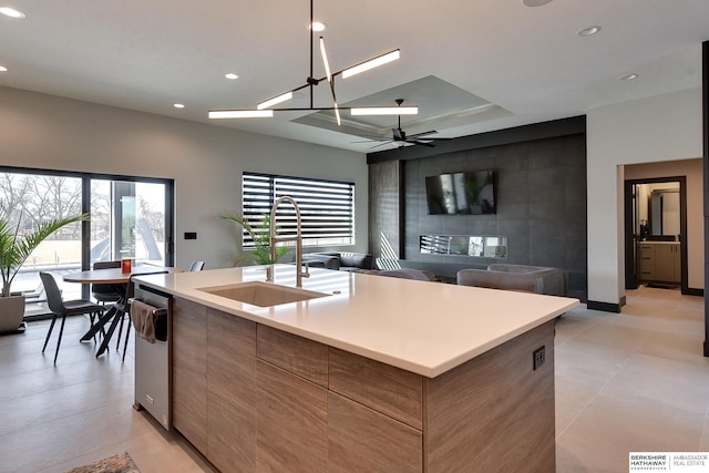 kitchen with modern cabinets, a kitchen island with sink, a sink, dishwasher, and ceiling fan