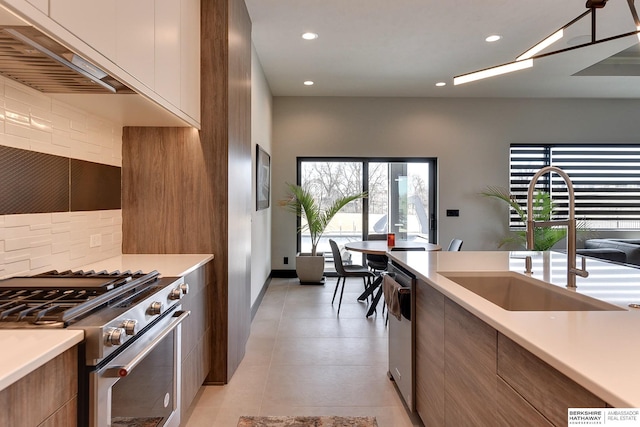 kitchen featuring modern cabinets, a sink, tasteful backsplash, appliances with stainless steel finishes, and brown cabinetry