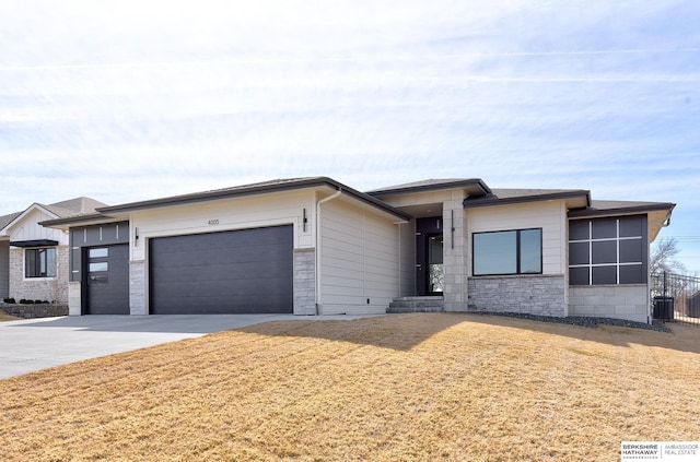 prairie-style house with stone siding, driveway, an attached garage, and fence