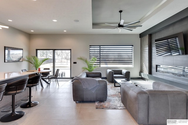 tiled living area with recessed lighting, a tray ceiling, and ceiling fan