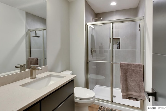 bathroom with vanity, a shower stall, and toilet